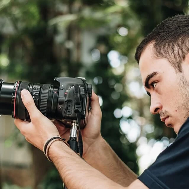 Rapaz segurando máquina fotográfica e olhando para a lente